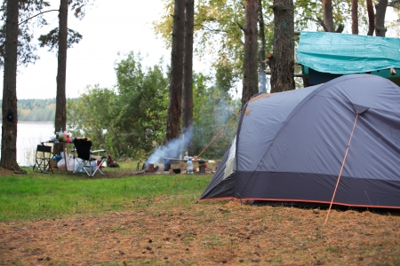 Camping with gray tent in forest near lakeの写真素材