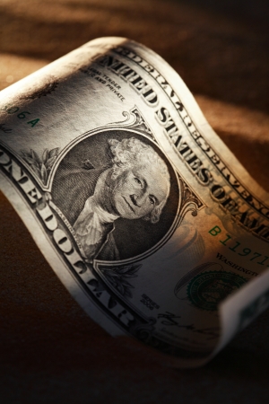 One dollar bank note closeup on dark sand background with shadowの写真素材