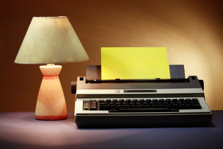 Electrical typewriter with blank yellow paper sheet near luminous desk lampの写真素材