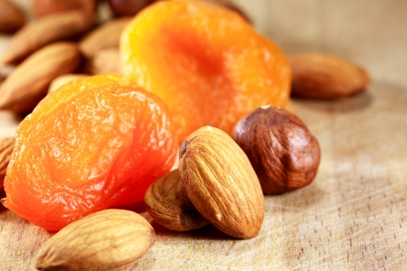 Closeup of dried apricots lying near almonds and filbert nuts on wooden backgroundの写真素材