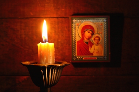 Closeup of lighting candle on wooden background with Christian iconの写真素材