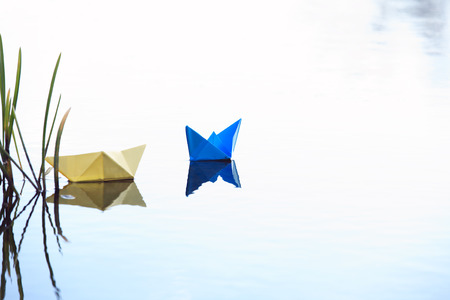 Two paper boats near grass on water surfaceの写真素材
