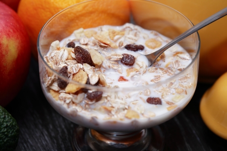 Glass bowl with muesli and milk near fruitsの写真素材