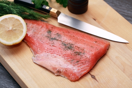 Salmon fillet on cutting board near knife and lemonの写真素材
