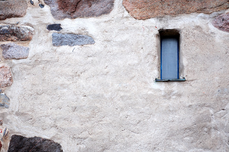 Old stone wall with small narrow window. の写真素材