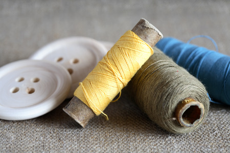 Sewing concept. Closeup of spools of thread near wooden buttons
