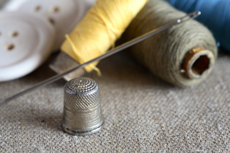 Sewing concept. Old thimble near spools of thread and wooden buttonsの写真素材