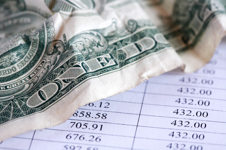 Business concept. Closeup of crumpled one dollar bank note on paper table with digitsの写真素材