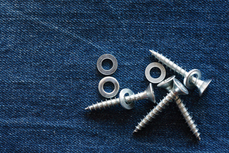 Few metal screws on blue denim backgroundの写真素材