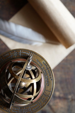 Vintage still life with Armillary sphere globe near quill and scroll