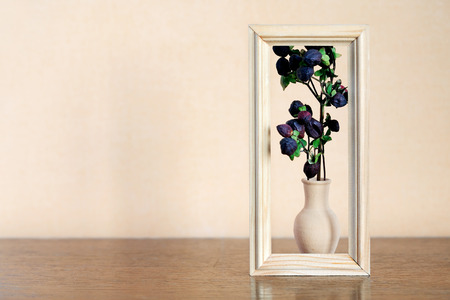 Nice dry plant with berries in elegance clay vase inside wooden frame