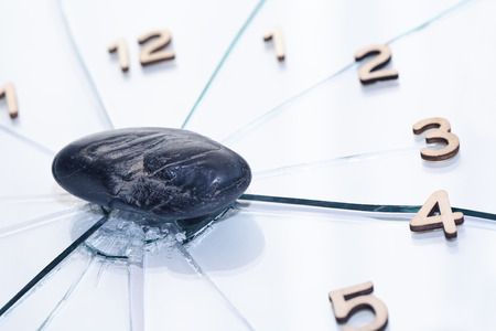 Black stone on shattered glass clock faceの写真素材