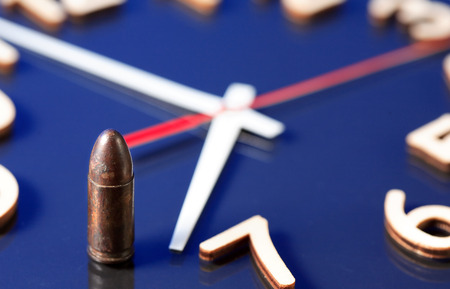 Gun cartridge standing on clock faceの写真素材