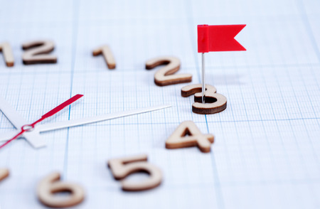 Deadline concept. Clock face with red flag pin on background with graph paperの写真素材