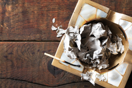 Burnt match on ashtray with paper ashes on wooden backgroundの写真素材