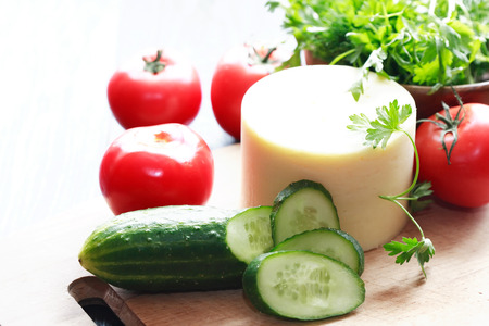 Closeup of cheese near sliced cucumber and tomatoesの写真素材