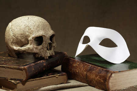 Death concept. Human skull on old book near white maskの写真素材