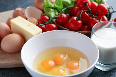 Bowl with raw eggs near various ingredients for omeletの写真素材