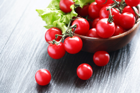 Wooden bowl with cherry tomatoes on black tableの写真素材