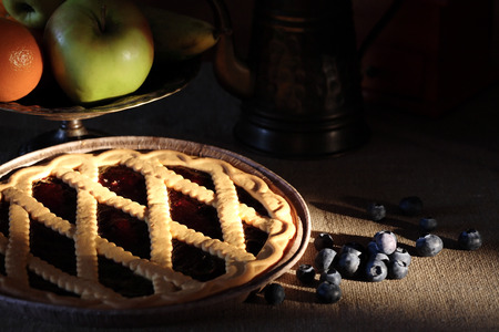 Dessert still life. Freshness homemade blueberry pie near fruit bowl on dark backgroundの写真素材
