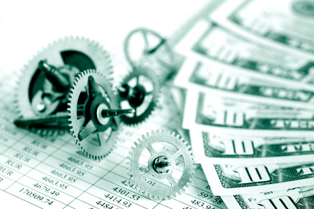 Closeup of gears and dollar bank notes on paper list with digitsの写真素材
