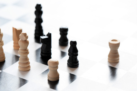 Black and white chessman set on chessboard against light