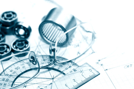 Industrial concept. Few ballbearings near ruler and spectacles on graph paper backgroundの写真素材