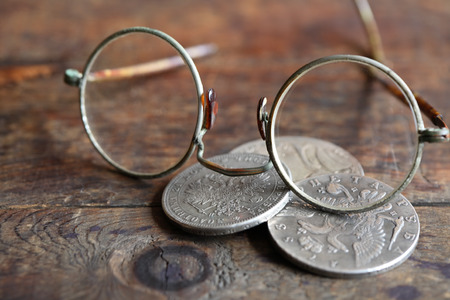 Three ancient Russian silver coins near spectacles on wooden backgroundの写真素材