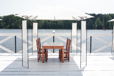 Summer vacation. Outdoor cafe with empty table and chairs near lakeの写真素材