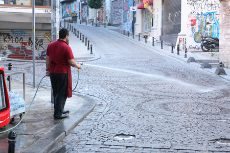 Istanbul, Turkey - July 5, 2015: Shop owner washing sreet early in the morningのeditorial素材