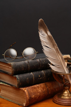 Literature concept. Vintage still life with quill pen near book and spectacles on dark backgroundの写真素材