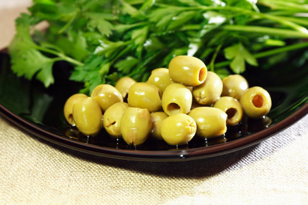 Green olives near parsley on black plate closeupの写真素材