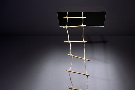 Escape concept. Rope ladder inside hatch in ceilingの写真素材