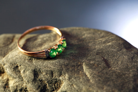 Gold ring with emerald on gray stone against nice dark backgroundの写真素材