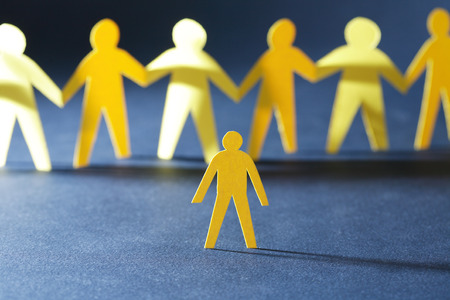 Robbery concept. Yellow paper man against crowd in a row on darkの写真素材