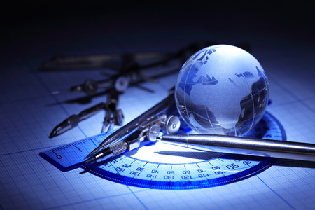 Education concept. Drawing instrument near glass globe on graph paper
