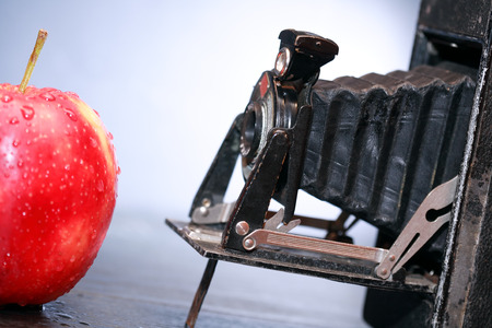 Old film camera against red apple on dark backgroundの写真素材