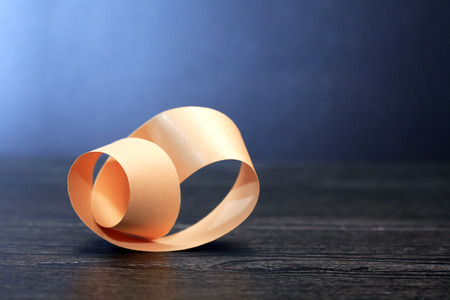 Paper Mobius strip on wooden board against dark backgroundの写真素材