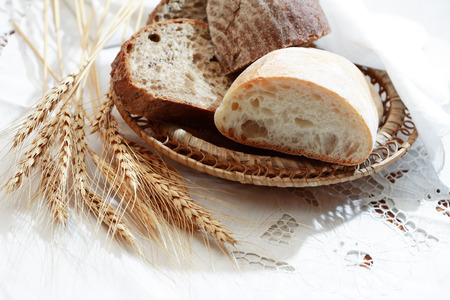 Farm still life. Freshness bread set on white tablecloth near wheat ears