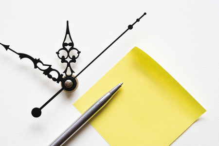 Reminder for business. Yellow paper for notes near clockの写真素材