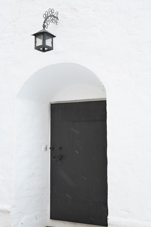 White Abbey wall with lantern and black door in archの写真素材