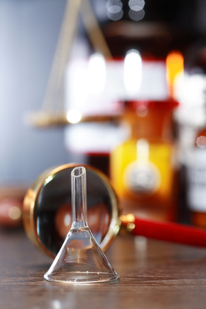 Chemical funnel near magnifying glass against blurred background with flasksの写真素材