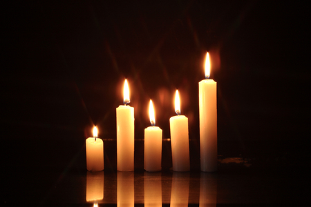 Few lighting candles in a row on dark backgroundの写真素材