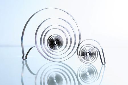 Industrial background. Two old metal spirals on glass surface with reflection