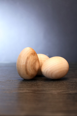Three wooden eggs on table against gray backgroundの写真素材