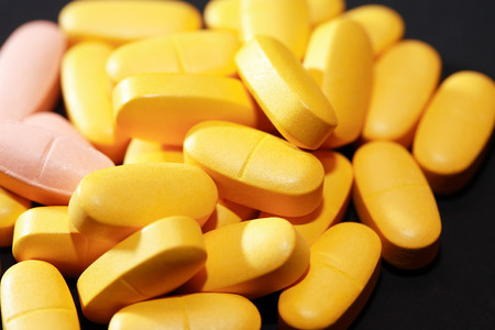 Closeup of various colored pills on dark backgroundの写真素材