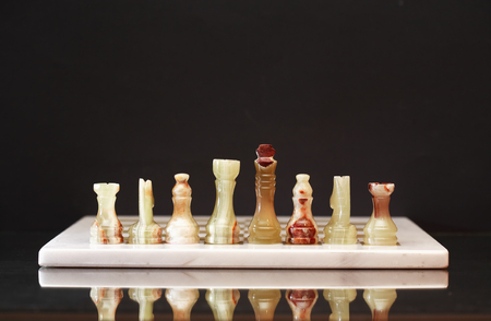 Set of chess pieces made from Onyx on board against dark backgroundの写真素材