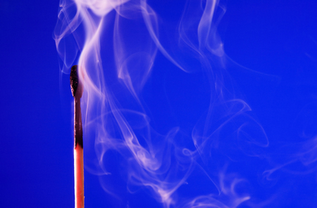 Extinguished match with smoke on blue backgroundの写真素材
