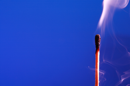 Extinguished match with smoke on blue backgroundの写真素材