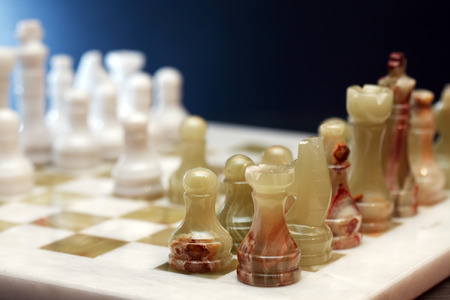 Set of chess pieces made from Onyx on board against dark backgroundの写真素材